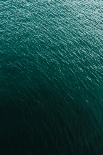 a person riding a surfboard on top of a body of water, an album cover, inspired by Elsa Bleda, trending on unsplash, hurufiyya, view from helicopter, dark green water, blue: 0.5, single color