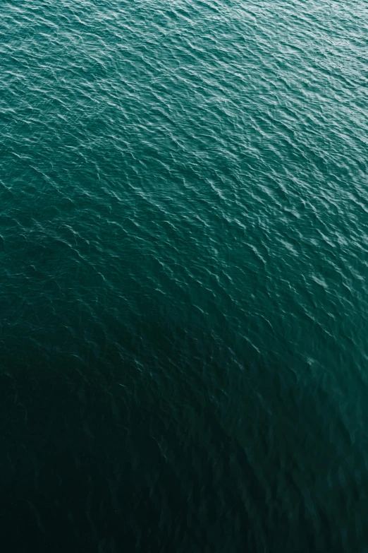 a person riding a surfboard on top of a body of water, an album cover, inspired by Elsa Bleda, trending on unsplash, hurufiyya, view from helicopter, dark green water, blue: 0.5, single color