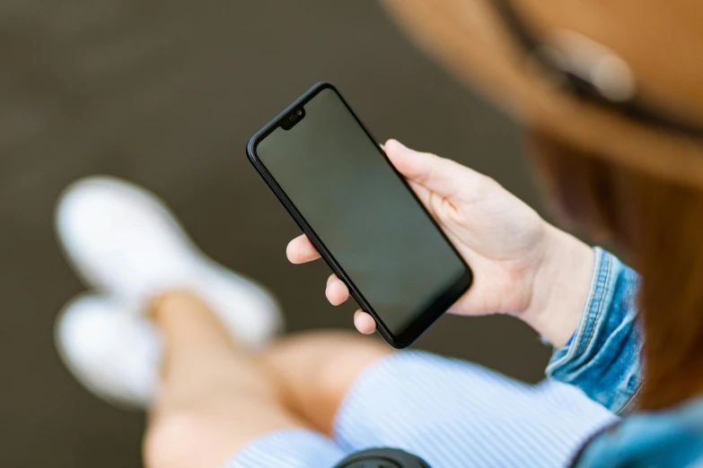 a close up of a person holding a cell phone, trending on pexels, square, black, test, sitting down