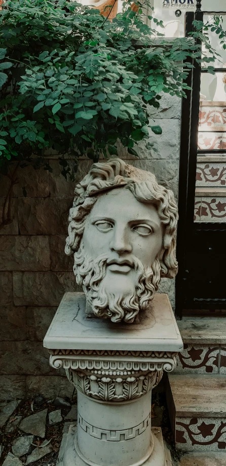 a statue of a man with a beard in front of a door, inspired by Exekias, trending on pexels, neoclassicism, square face, jimin\'s grecian nose, face covered in dirt, laurel wreath on his head