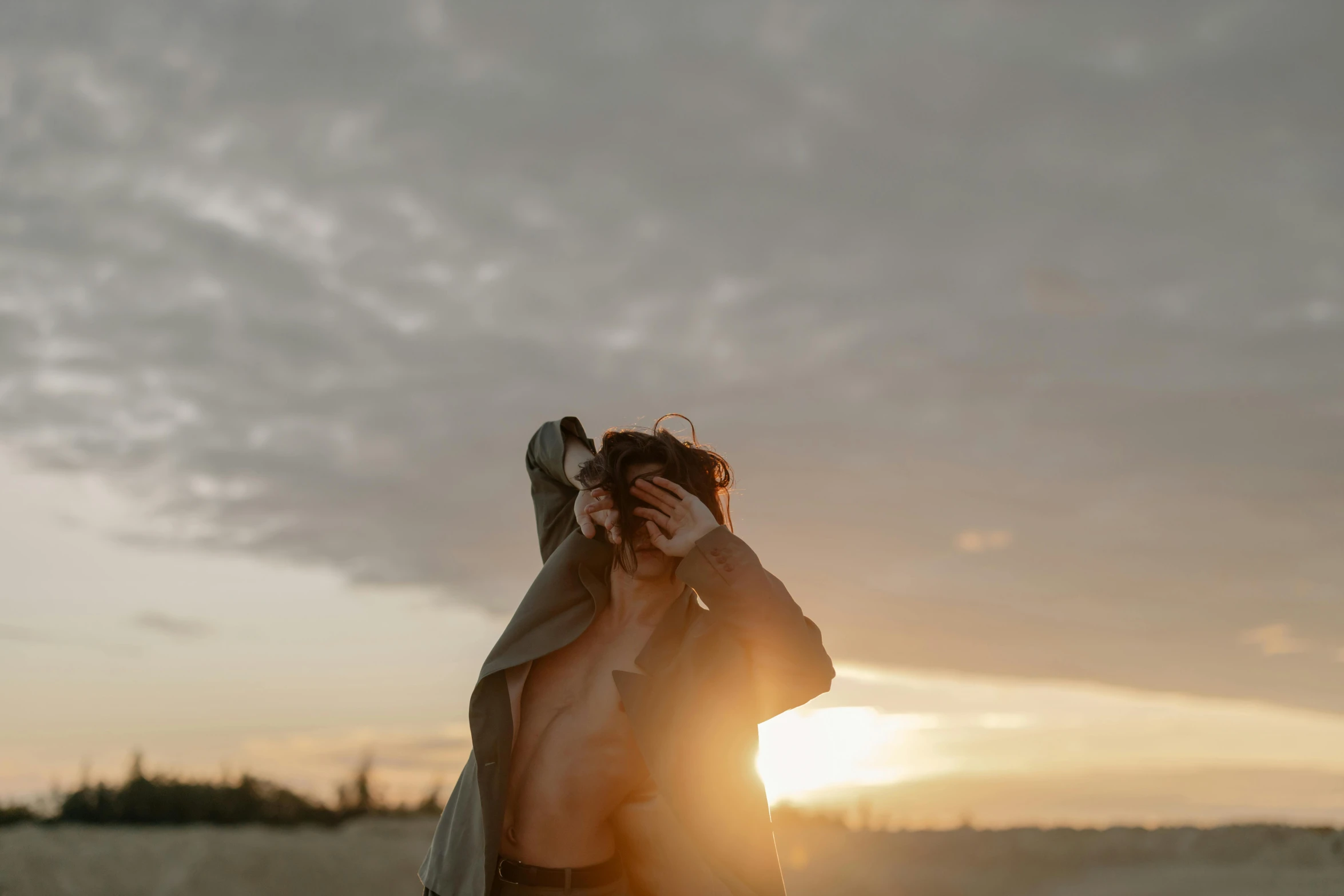 a woman standing on top of a sandy beach, a picture, by Emma Andijewska, trending on pexels, happening, light over boy, disrobed, hair over face, sunraise