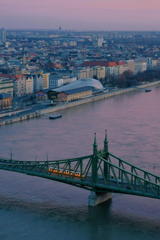 a bridge over a body of water with a city in the background, inspired by Otakar Sedloň, pexels contest winner, happening, monorail, promo image, high angle, evening light
