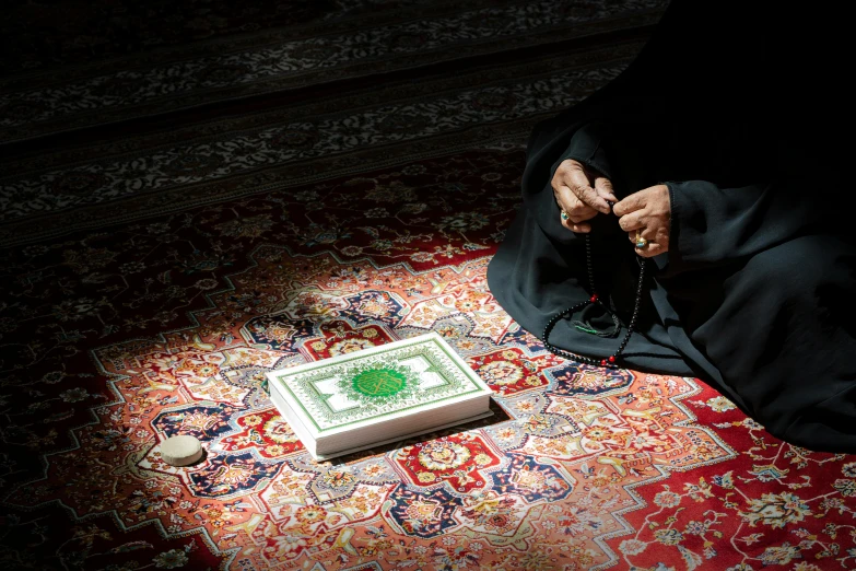 a close up of a person sitting on a rug, an album cover, shutterstock, hurufiyya, islam, puṣkaracūḍa, lpoty, rectangle