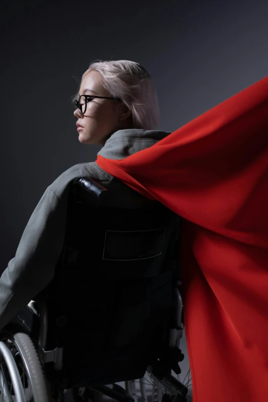 a woman in a wheelchair with a red cape, an album cover, inspired by Bernardino Mei, wearing space techwear, gabe newell as a superman, marvelous designer, hong june hyung