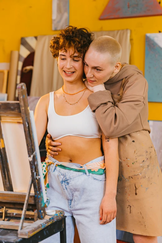 a couple of women standing next to each other, a painting, trending on pexels, feminist art, shaved head, hugging, bralette, art student