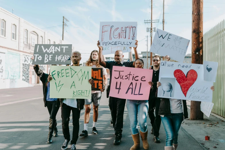 a group of people walking down a street holding signs, by Julia Pishtar, trending on pexels, jemal shabazz, los angeles ca, justice, avatar image