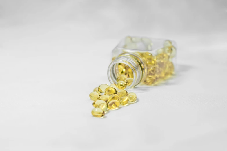 a bottle filled with fish oil sitting on top of a white surface, a picture, by Matija Jama, pexels, yellow crystal gem, yellow lanterns, hd footage, golden teeth