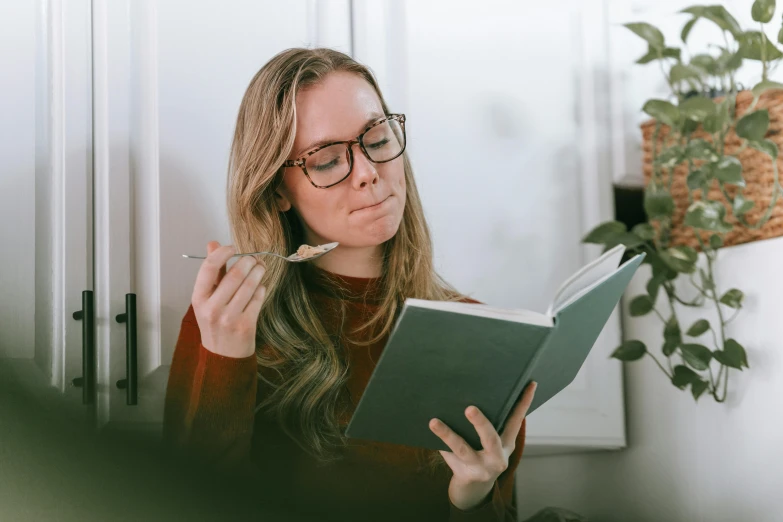 a woman in glasses is reading a book, a sketch, pexels contest winner, eating, avatar image, sydney hanson, high quality image