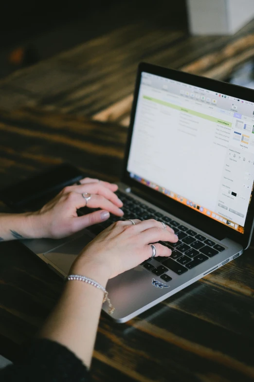 a woman typing on a laptop computer on a wooden table, by Carey Morris, pexels, multiple stories, email, wide screenshot, technical