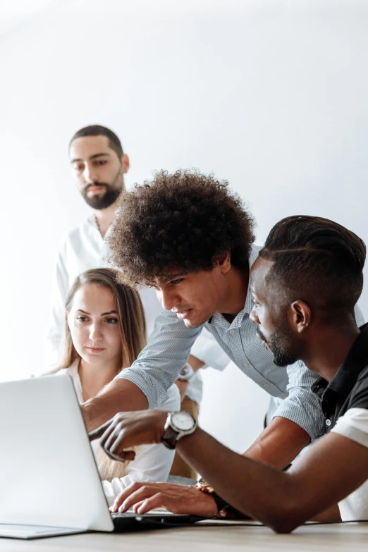 a group of people sitting around a table looking at a laptop, varying ethnicities, on grey background, black man with afro hair, looking at monitor