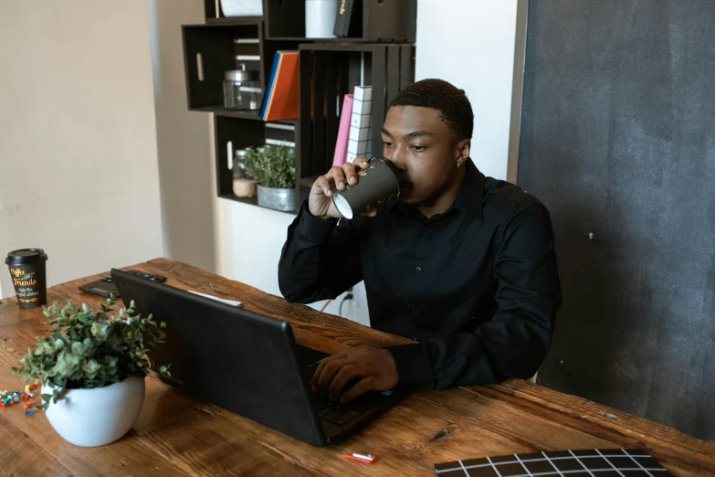 a man that is sitting at a table with a laptop, drinking a coffee, abcdefghijklmnopqrstuvwxyz, ( ( dark skin ) ), curated collections