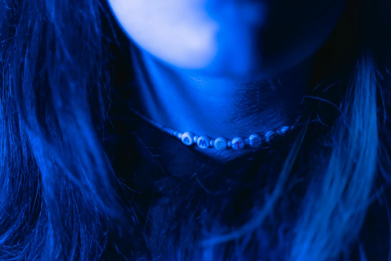 a close up of a person wearing a necklace, an album cover, inspired by Elsa Bleda, trending on pexels, antipodeans, blue bioluminescence, 8k 50mm iso 10, blue monochromatic, teenage girl