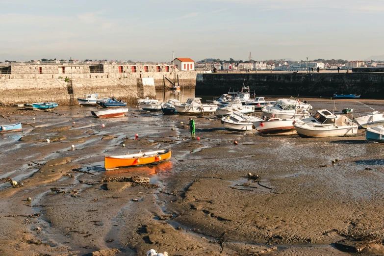 a group of boats sitting on top of a sandy beach, by Cricorps Grégoire, pexels contest winner, les nabis, harbour in background, large cracks, thumbnail, early evening