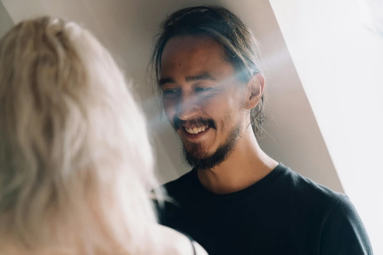 a man standing next to a woman in a room, a character portrait, by Lee Loughridge, pexels contest winner, light and space, smiley profile, shaven stubble, haze over the shoulder shot, lachlan bailey