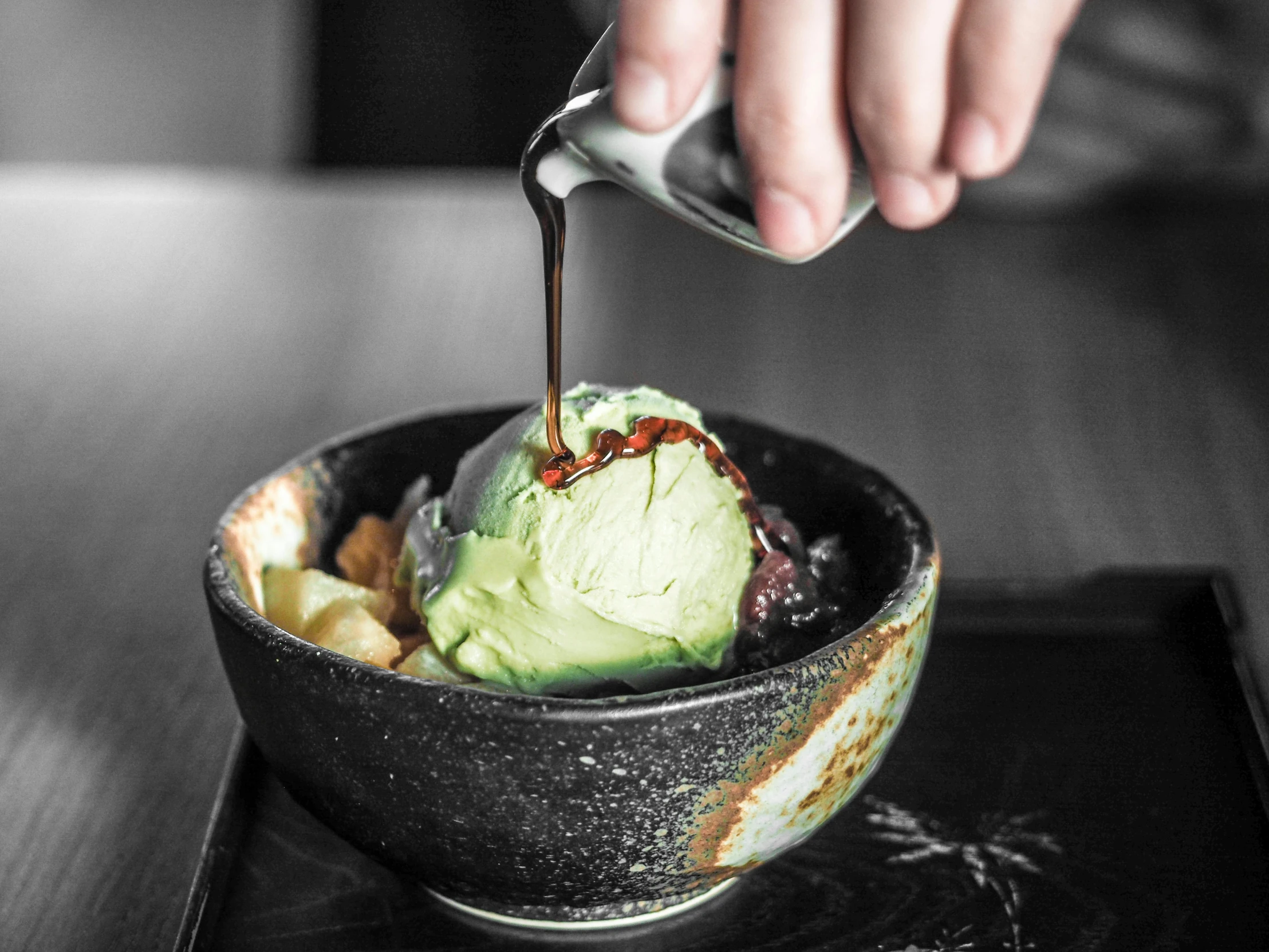 a person dipping something into a bowl of food, ice cream, black and green, ukiyo, central shot