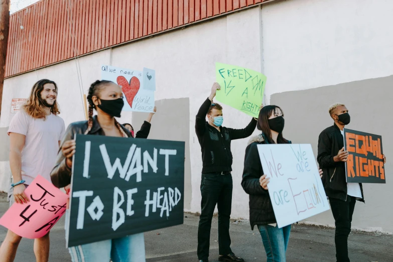 a group of people holding signs in front of a building, trending on pexels, jovana rikalo, panel of black, heath clifford, anfree wallin