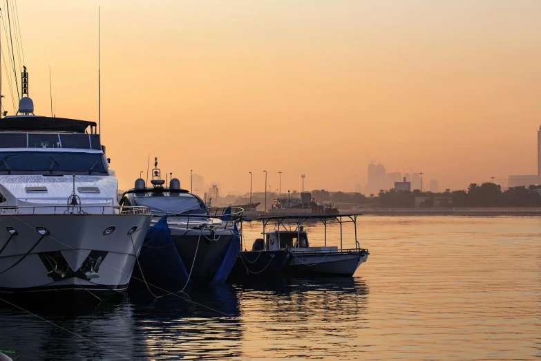 a number of boats in a body of water, by Emanuel Witz, pexels contest winner, hurufiyya, humid evening, gta : dubai, soft morning light, seen from the side