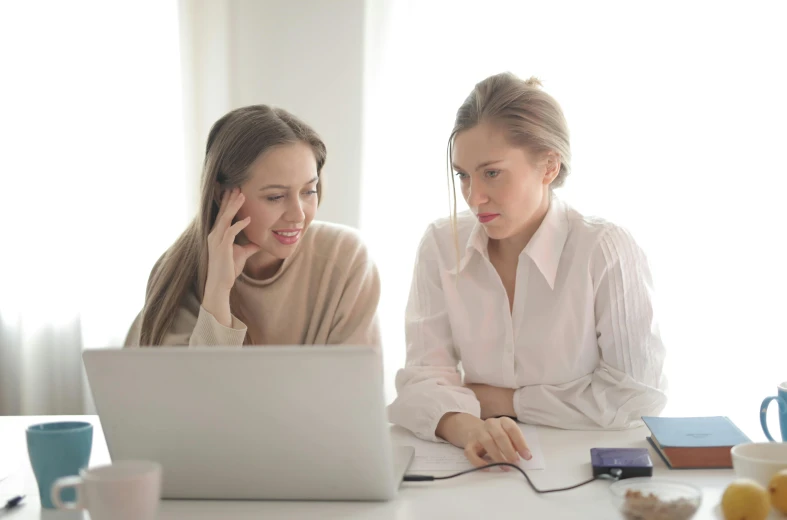 two women sitting at a table looking at a laptop, trending on pexels, avatar image, background image, wearing a white blouse, various posed