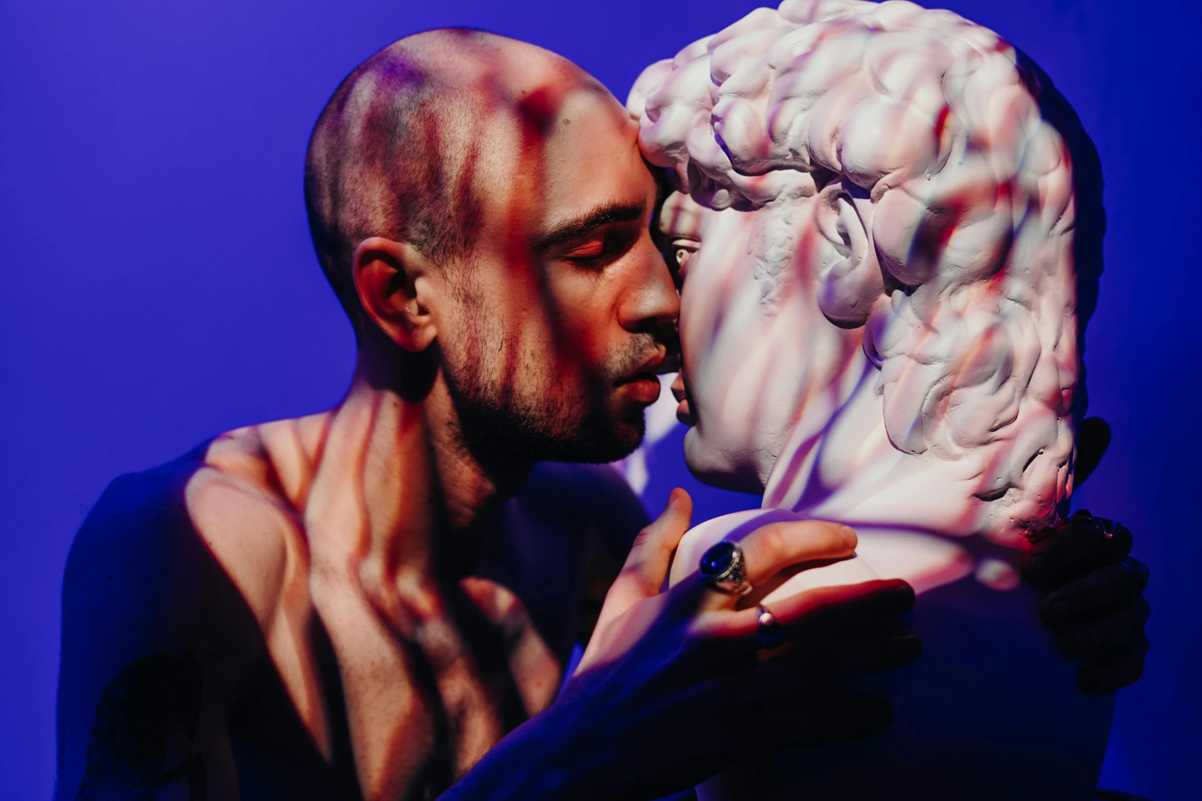 a man kissing a statue in front of a blue background, by Alexis Grimou, pexels contest winner, mannerism, purple aethetic, still from a music video, adam and eve inside the brain, lachlan bailey