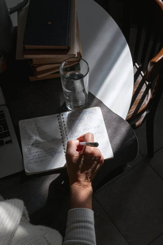 a person sitting at a table with a laptop and notebook, pexels contest winner, realism, light and shadow, filling with water, high angle shot, essence