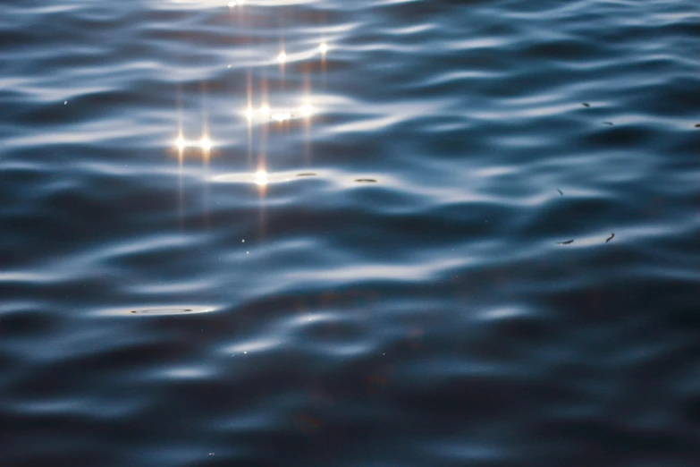 the sun shines brightly on the surface of the water, a picture, by Jan Rustem, unsplash, light and space, stars reflecting on the water, wavy water, soft sunlight dappling, deep blue mood