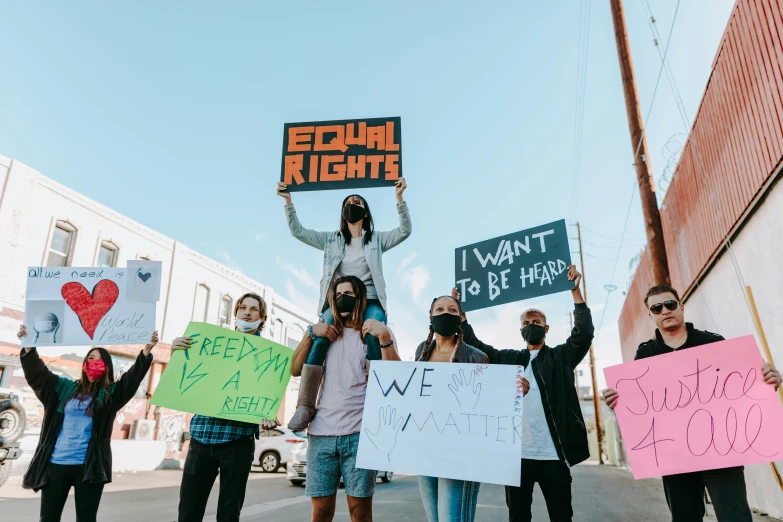 a group of people holding up signs on a street, trending on pexels, gay rights, background image, fight, high resolution