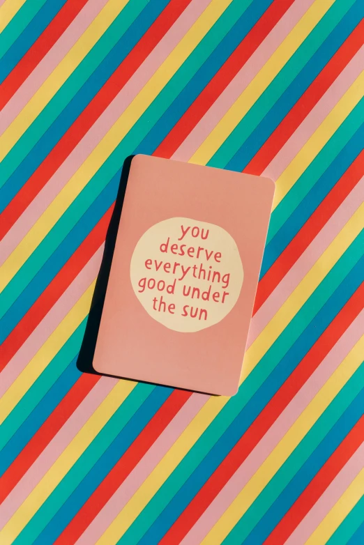 a card sitting on top of a colorful striped surface, a picture, the sun at their back, holding notebook, you won't believe it, feeling good