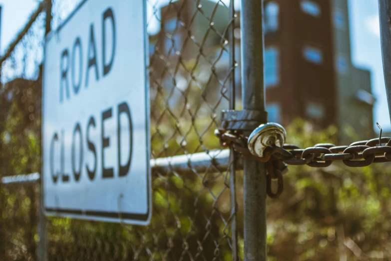 a road closed sign on a chain link fence, a photo, unsplash, graffiti, background image, tilt shift”, an abandoned, 🚿🗝📝