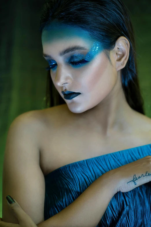 a woman in a blue dress holding a cell phone, an album cover, trending on pexels, art photography, dark glitter makeup, bodypainting, ariana grande as a mermaid, fierce look