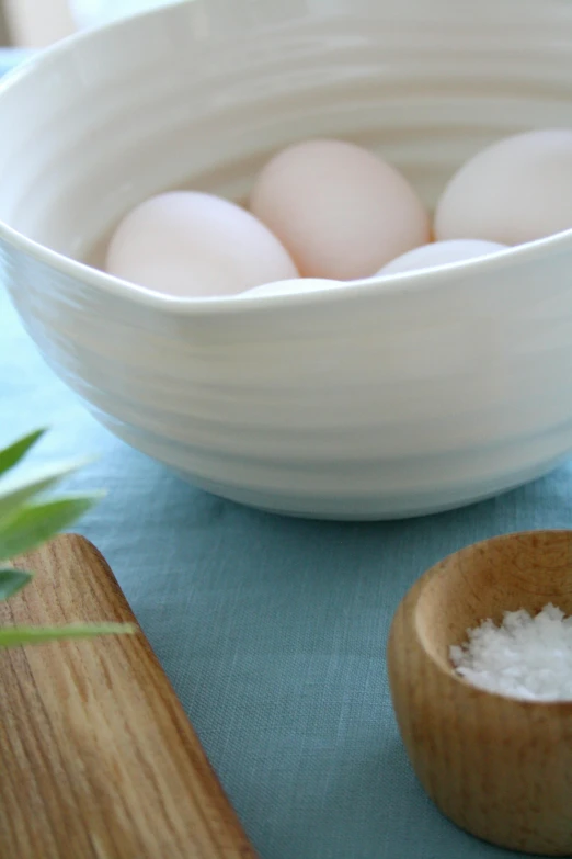 a bowl of eggs sitting on top of a table, by Alice Mason, organic ceramic white, seaside, medium detail, ingredients on the table