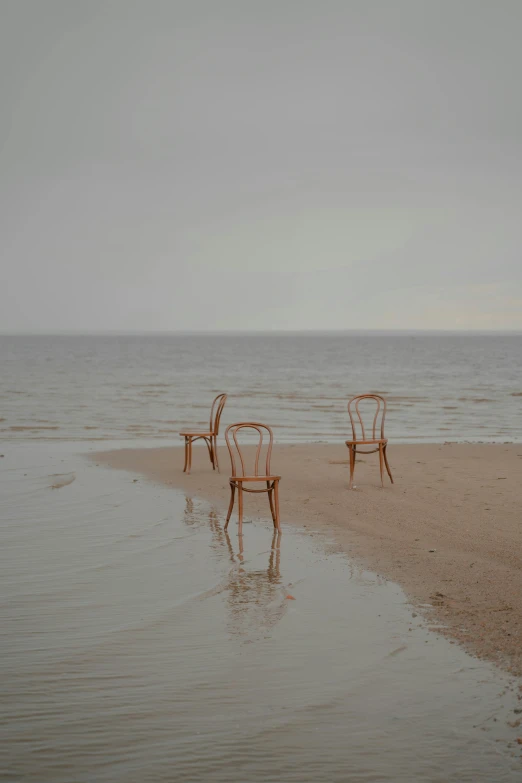 a couple of chairs sitting on top of a sandy beach, inspired by Anna Füssli, unsplash, conceptual art, melting and dripping. eerie, rule of three, standing next to water, ( ( photograph ) )