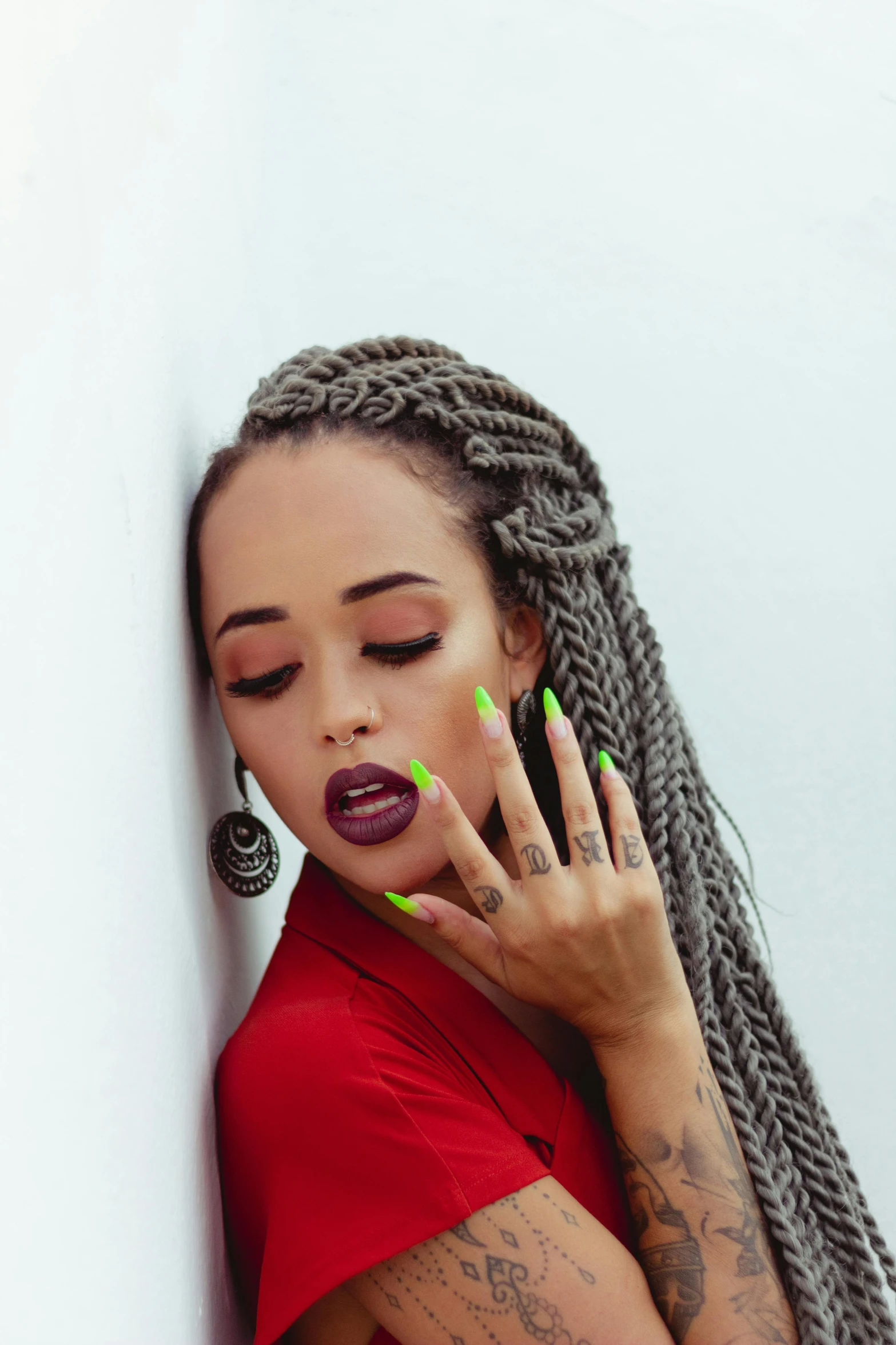 a woman with green nails leaning against a wall, inspired by Dulah Marie Evans, trending on pexels, vanessa morgan, braids, thick red lips, dreadlock breed hair