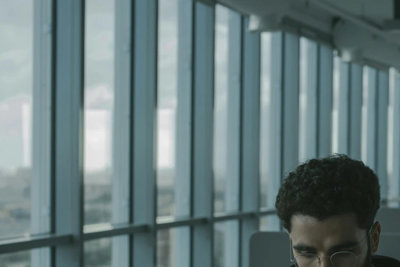 a man sitting in front of a laptop computer, by Alejandro Obregón, pexels contest winner, serial art, still from a terence malik film, in an call centre office, with afro, overcast! cinematic focus