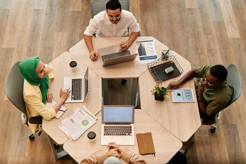 a group of people sitting around a table with laptops, trending on pexels, renaissance, round design, wooden, offices, hexagonal shaped