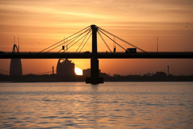 a bridge over a body of water at sunset, by Jan Tengnagel, pexels contest winner, hurufiyya, memphis, from luxor, port city, istockphoto