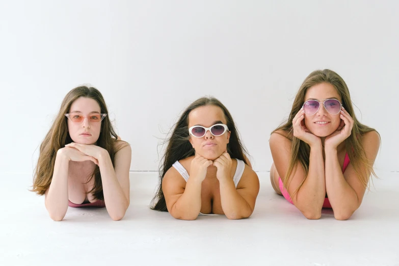 a group of young women laying on top of a white floor, unsplash, aestheticism, with square glasses, ((purple)), brunette, pokimane