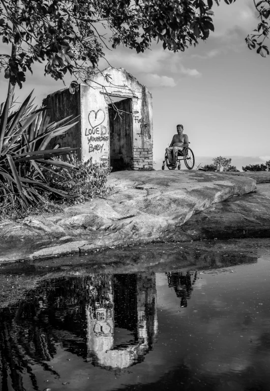 a man riding a bike next to a body of water, a black and white photo, by Joze Ciuha, process art, sitting in a wheelchair, a portal to the depths, art foreground : eloy morales, everything seems abandoned