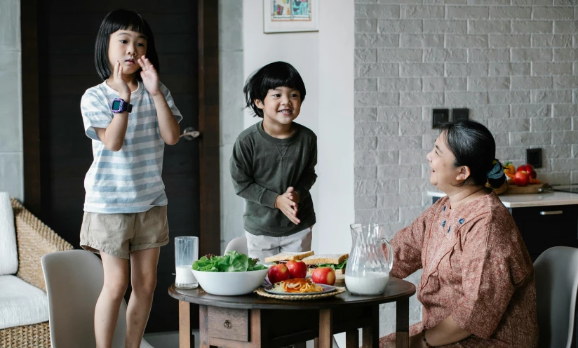 a group of people standing around a table with food on it, with a kid, asian human, older brother vibes, ad image