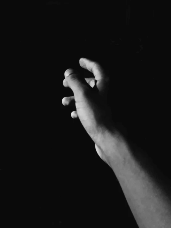 a black and white photo of a hand reaching for something, inspired by Roy DeCarava, unsplash, praying posture, instagram post, video still, dark