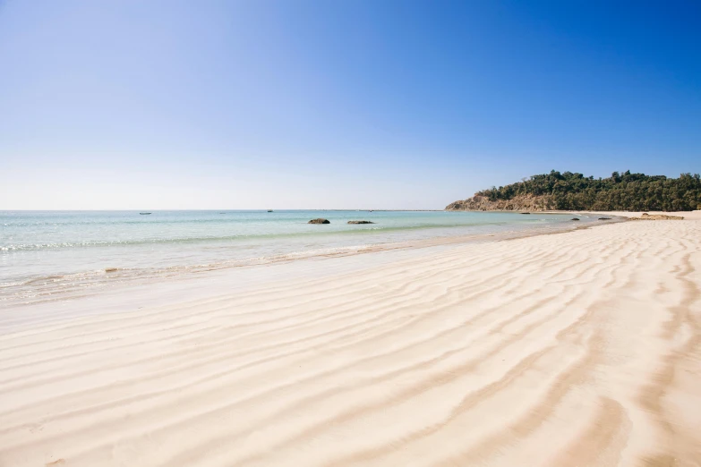 a sandy beach next to the ocean on a sunny day, unsplash contest winner, straya, extremely clear and coherent, pale light, mango