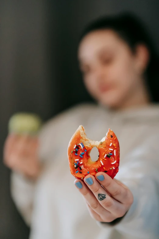 a woman holding a donut with sprinkles on it, a picture, by Julia Pishtar, trending on pexels, made of glazed, biological photo, michael angelo inspired, cavities