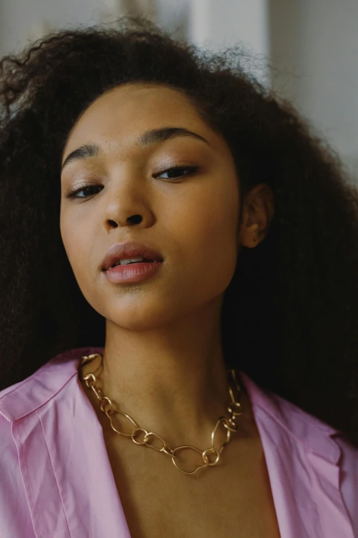 a woman with long hair wearing a pink shirt, inspired by Sophia Beale, trending on pexels, wearing a gold chain, mixed race woman, wearing gold jewellery, sza