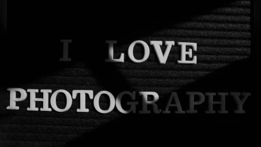 a black and white photo of the words i love photography, a black and white photo, inspired by Arnold Newman, pixabay, art photography, shot at dark with studio lights, colour hd photography, pinhole photo quality, still life photo of a backdrop