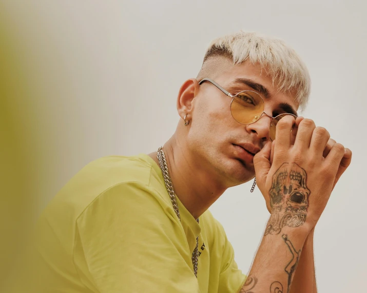 a man with a tattoo on his arm, an album cover, trending on pexels, yellow carrera glasses, zaha hadi, an epic non - binary model, nice afternoon lighting