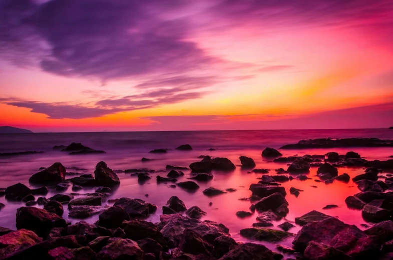 a sunset over the ocean with rocks in the foreground, pexels contest winner, purple and red, vibrant pink, ((sunset)), color photography