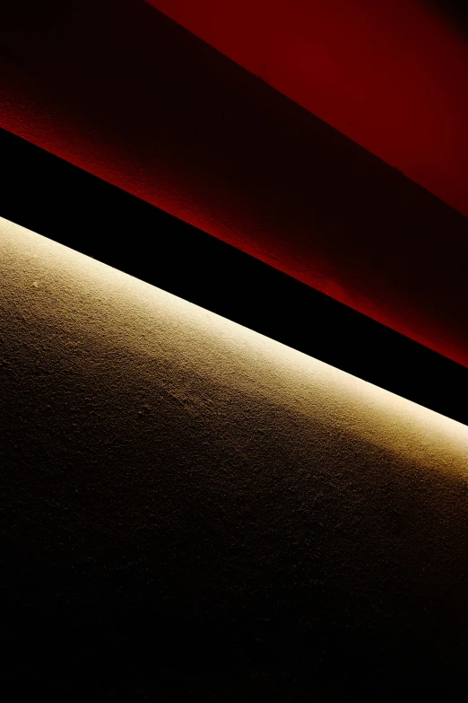a close up of a light on a wall, an album cover, by Doug Ohlson, unsplash, light and space, red black white golden colors, lines of lights, ceiling hides in the dark, side light