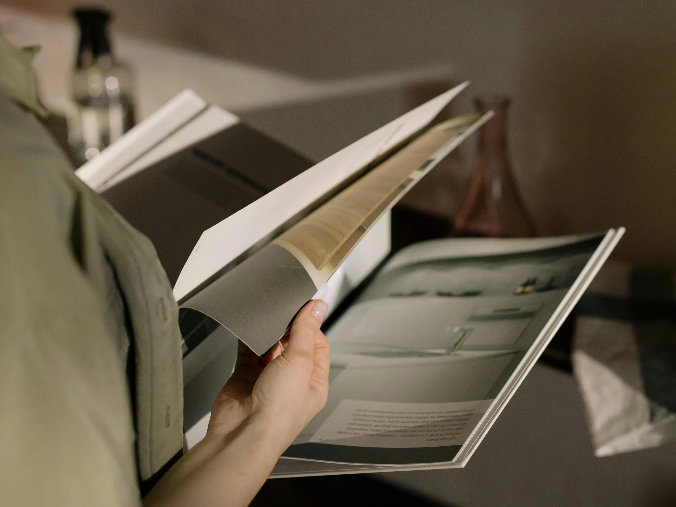 a person reading a book on a desk, inspired by Anna Füssli, unsplash, hyperrealism, brochure, close up shot from the side, sustainable materials, folded