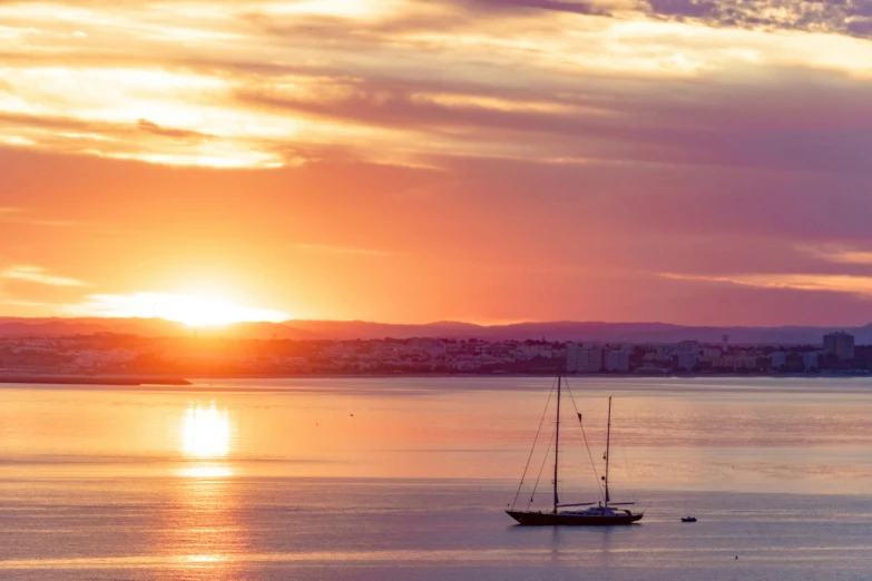 a couple of boats floating on top of a body of water, by Simon Marmion, pexels contest winner, romanticism, sunset panorama, lisbon, sailboat, wellington