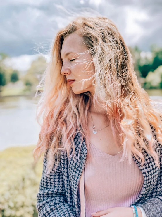 a woman standing in front of a body of water, trending on unsplash, light pink hair, curly dirty blonde hair, on a cloudy day, different hair colours