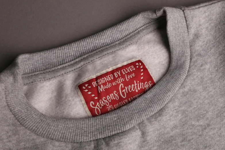 a grey shirt with a red label on it, a silk screen, inspired by Ernest William Christmas, wearing a sweater, medium close shot, precious moments, labels